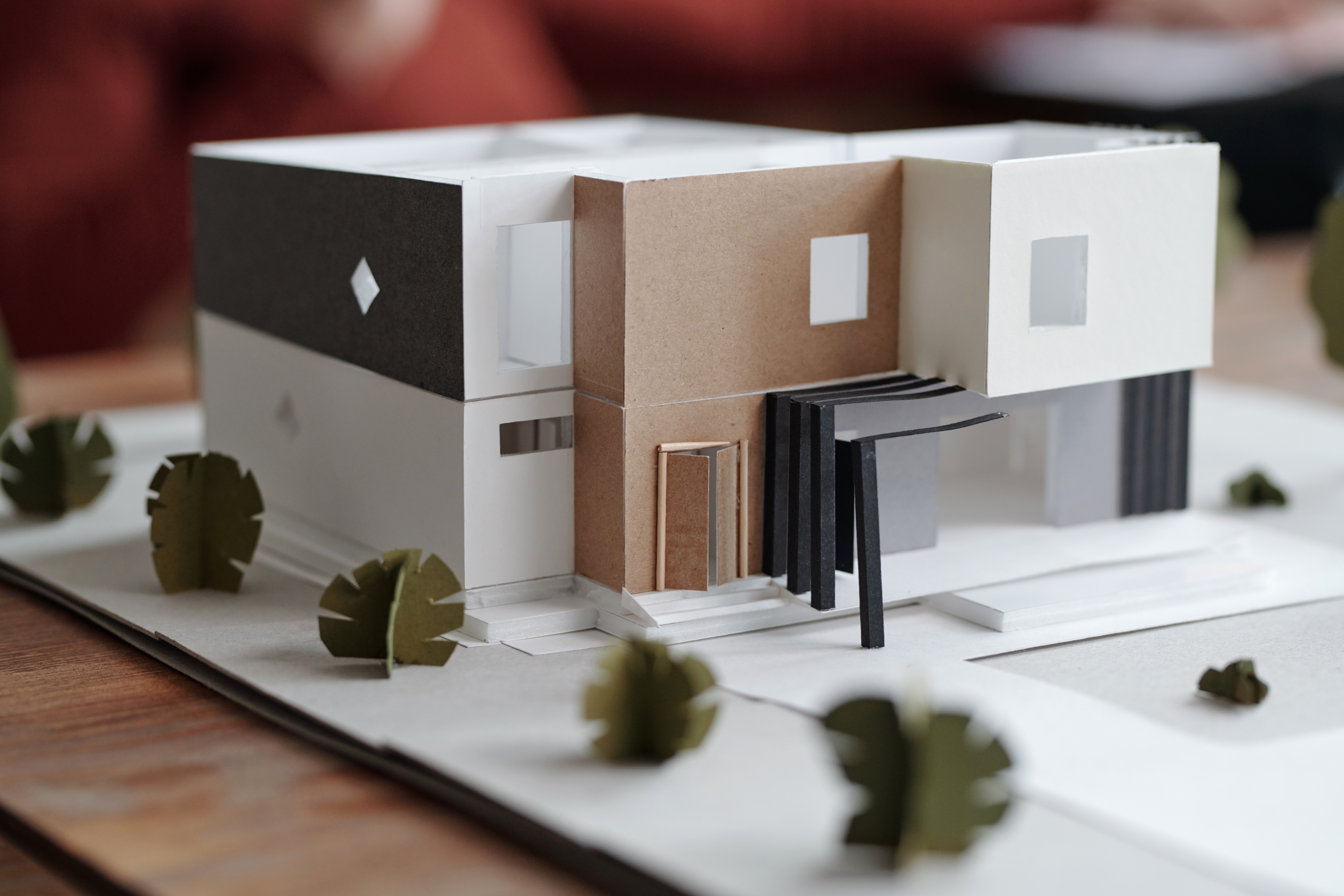 Close-up of cardboard 3D model of contemporary house in black and white colors standing between cardboard bushes
