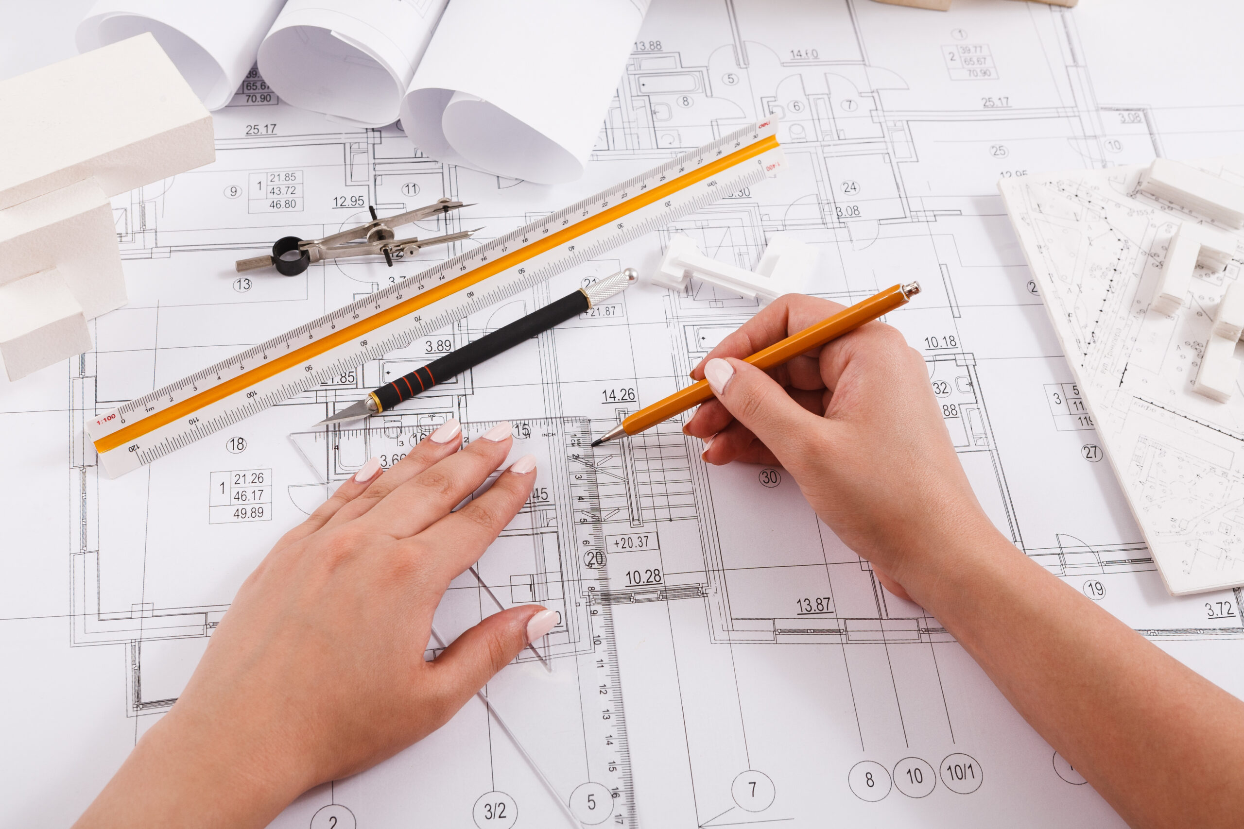 Architect drawing architectural project. Unrecognizable designer hands working with building blueprint, copy space