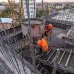 Operai versano calcestruzzo nei casseri per la realizzazione della struttura portante di un edificio in costruzione a Napoli.
