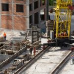 Operai e gru in cantiere edile a Napoli durante la costruzione di una struttura in cemento armato.