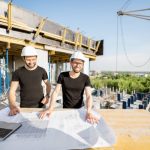 Due tecnici di Forma Costruzioni al lavoro su un progetto edile sostenibile a Napoli, con planimetrie e tecnologie innovative per edifici efficienti e moderni.