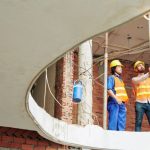 Operai e tecnici in cantiere durante una ristrutturazione a Napoli, con ponteggi e sopralluogo strutturale per valutare gli interventi necessari.